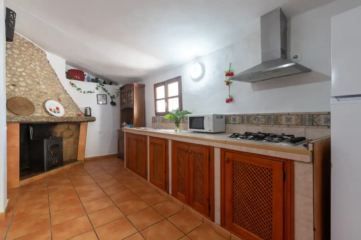 A kitchen with wooden cabinets, a cooktop, and a fireplace.