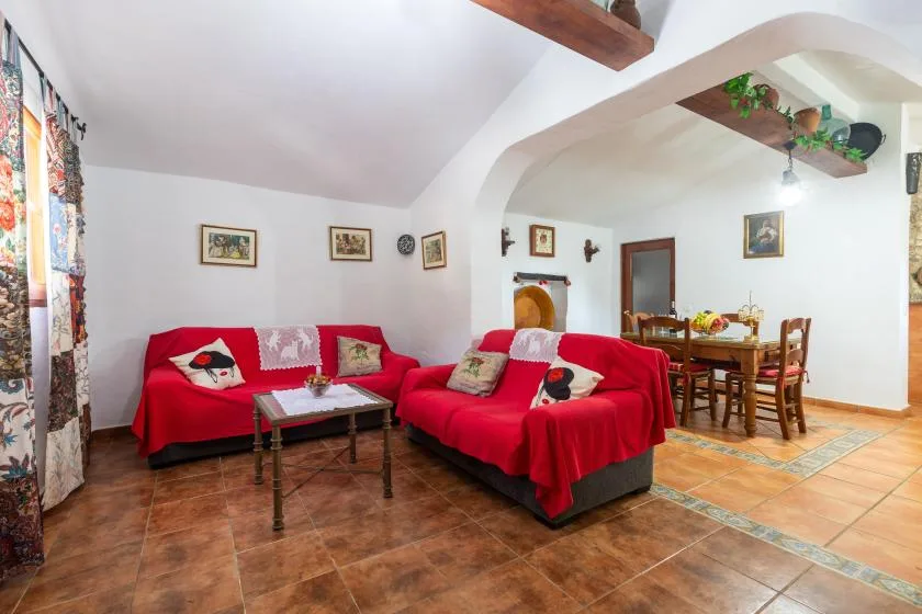A living room with red seating and a dining table in the adjoining space.