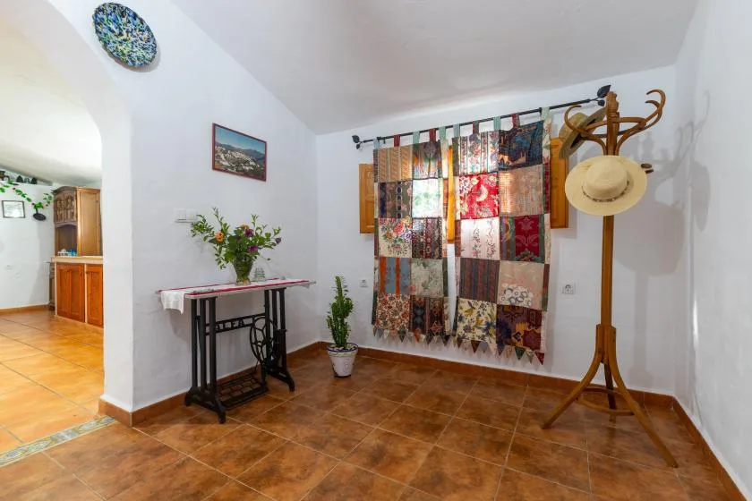 A bright room with a colorful patchwork wall hanging and a wooden coat stand.