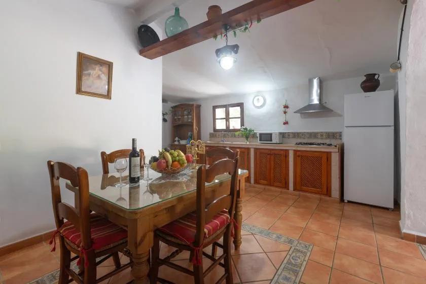 A dining area opens onto a kitchen with wooden cabinets and a tiled floor.