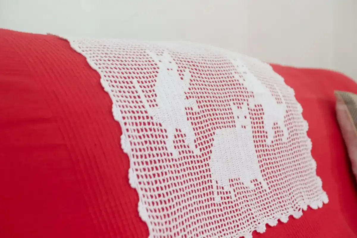 A red sofa with a white crocheted throw draped across it.