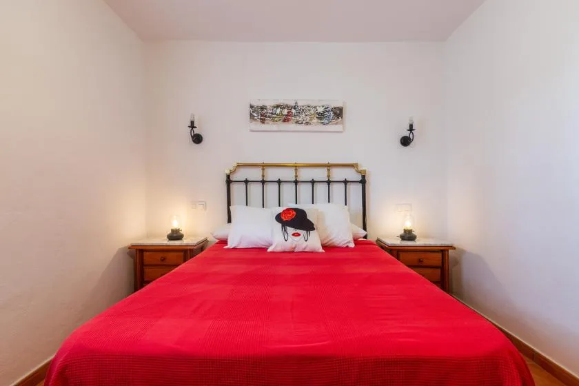 A bedroom with a bed covered in a bright red bedspread.