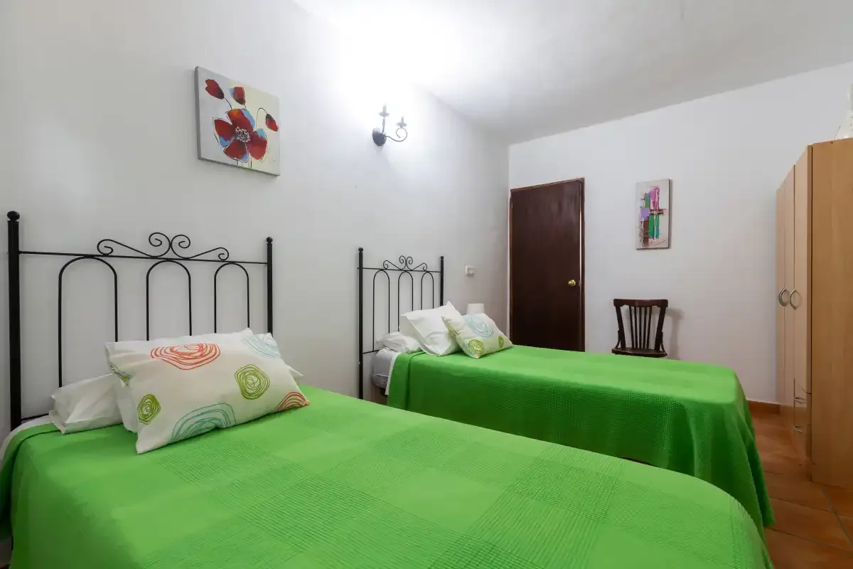 A bedroom with two beds covered in bright green bedspreads.