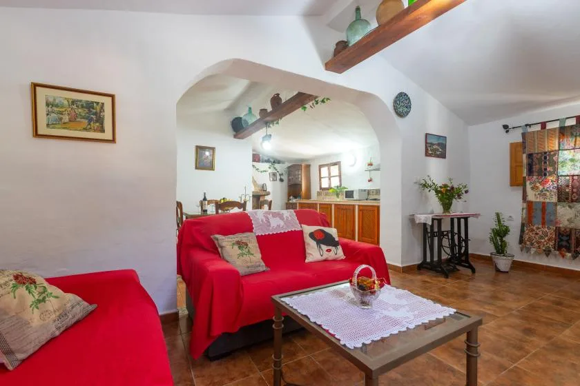A living room with red seating, a coffee table, and an adjoining kitchen.