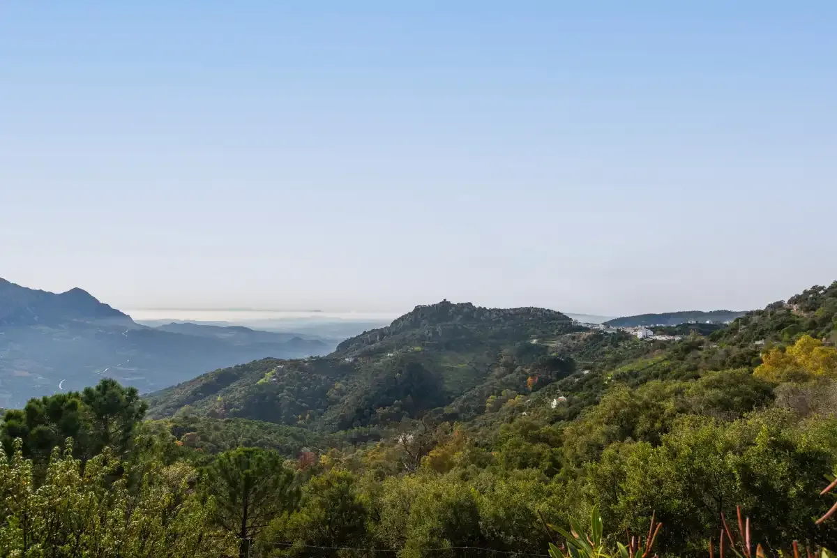 A broad mountain landscape with wooded hills beneath a clear sky.