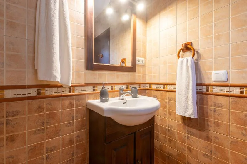 A tiled bathroom with a sink, mirror, and hanging towels.