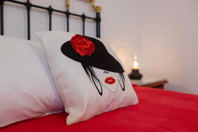 A bedroom bed with white pillows and a red bedspread.