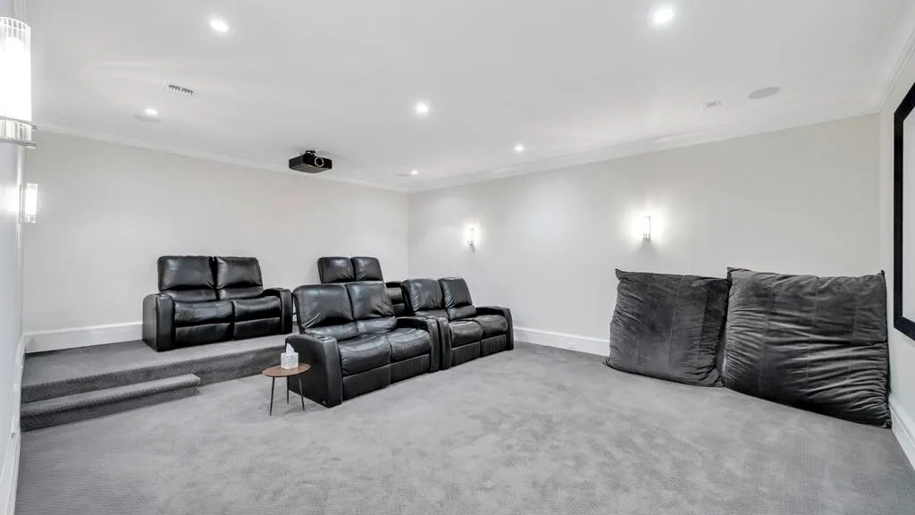 Una sala de cine en casa con asientos oscuros y un proyector.