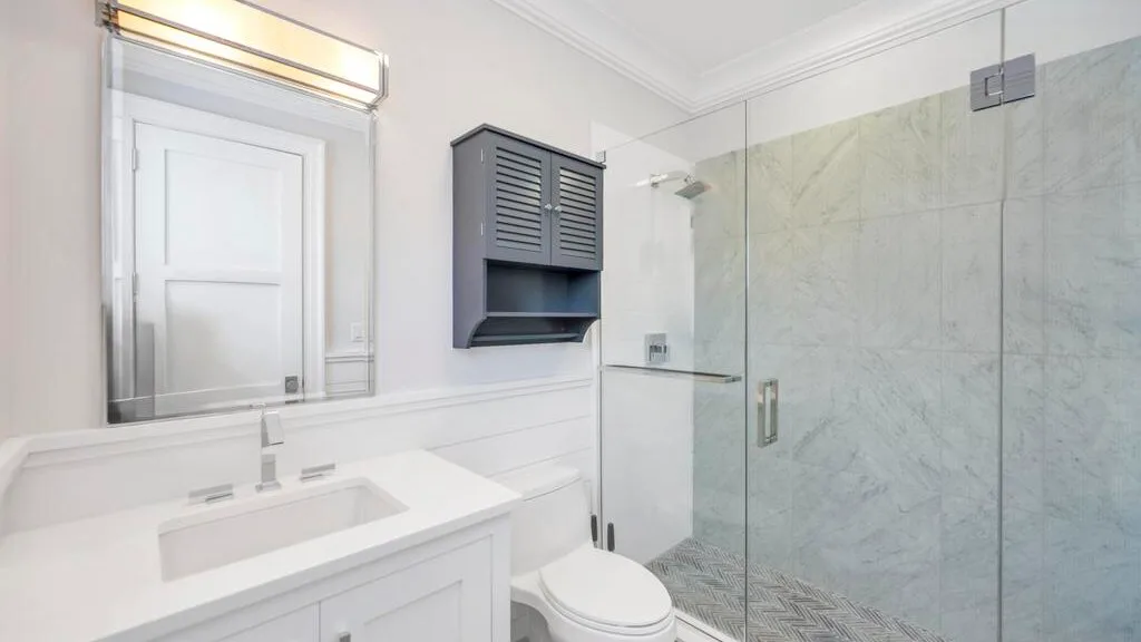 Un baño luminoso con lavabo blanco y ducha de vidrio.