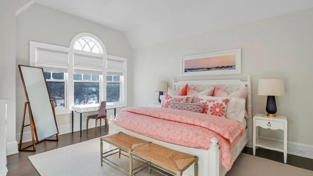 Un dormitorio luminoso con una cama rosa y grandes ventanas.