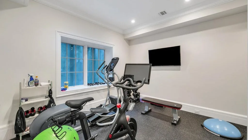 Un gimnasio en casa con equipos de cardio y un disco de equilibrio azul.