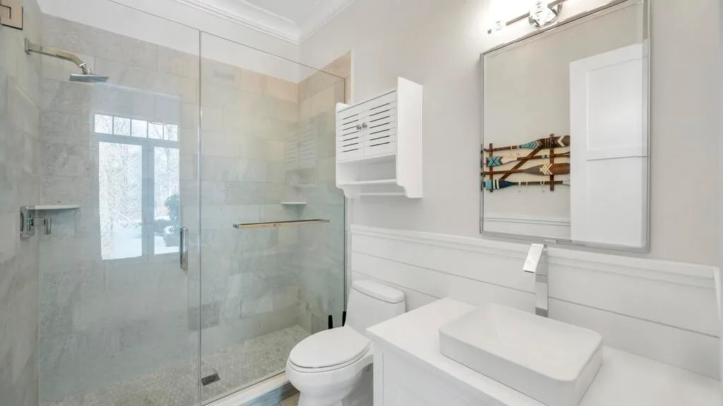 Un baño luminoso con ducha de vidrio, inodoro y lavabo.