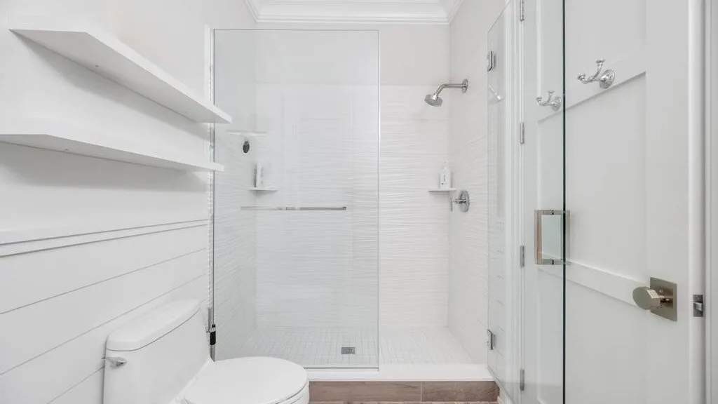 Un baño blanco con una ducha de vidrio y un inodoro.