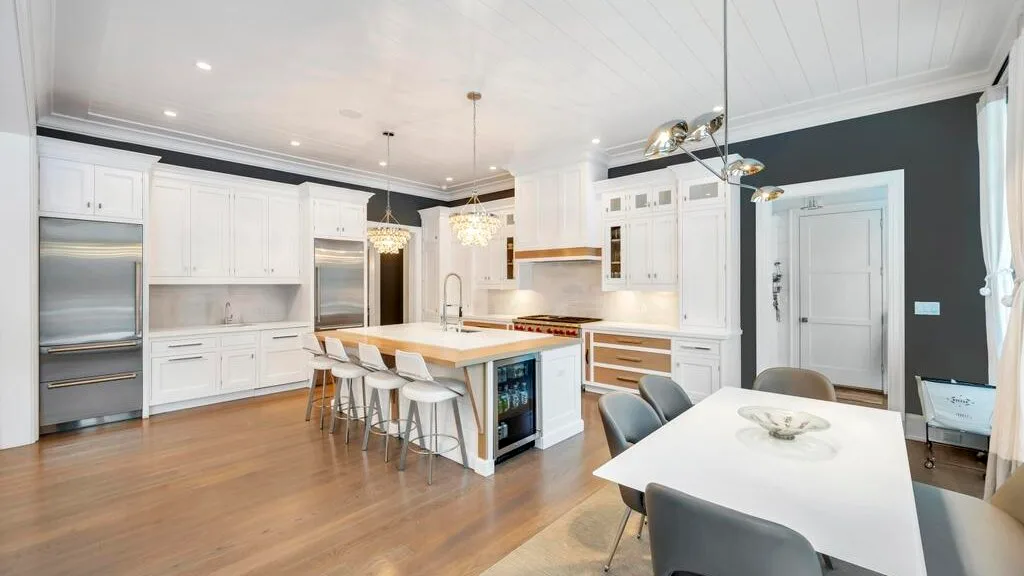 Una cocina y comedor luminosos con armarios blancos e isla central.