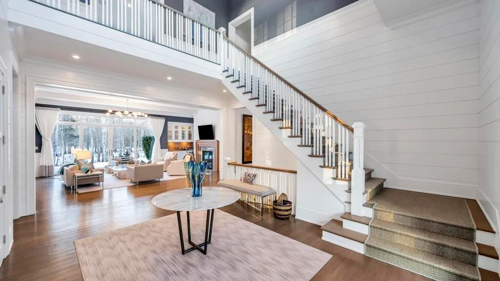 Una sala luminosa con una escalera y una barandilla en el nivel superior.