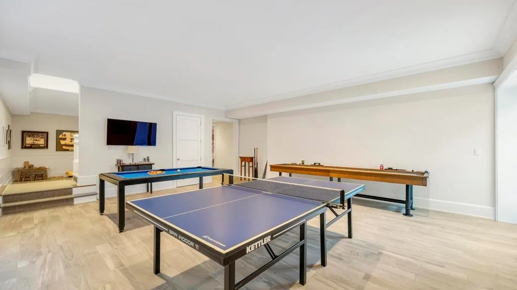 Una sala de recreación con una mesa de ping-pong y una mesa larga de juego.
