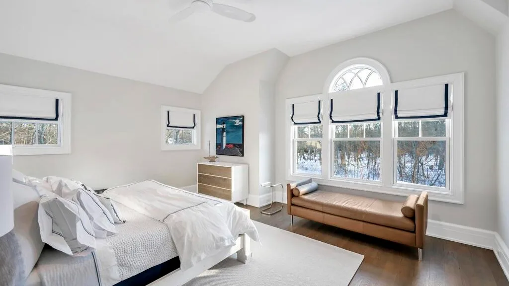 Un dormitorio luminoso con una cama y una gran ventana sobre una zona de estar.