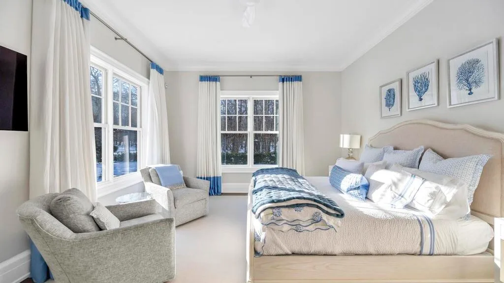 Un dormitorio luminoso con una cama grande, detalles azules y ventanas.
