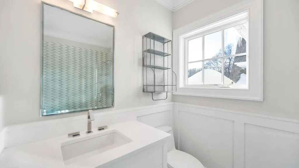 Un baño luminoso con lavabo, espejo y ventana.