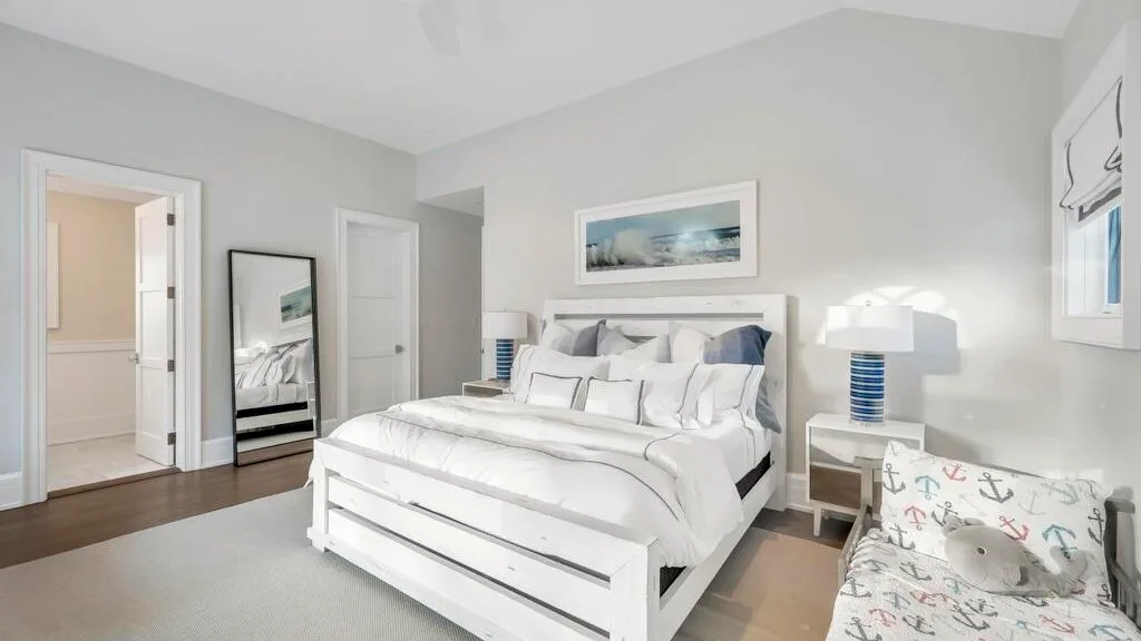 Un dormitorio luminoso con una cama blanca y mesas de noche a juego.