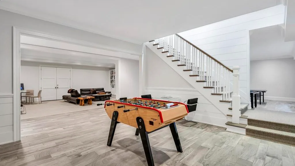 Una luminosa sala de estar con una mesa de futbolín y una escalera.