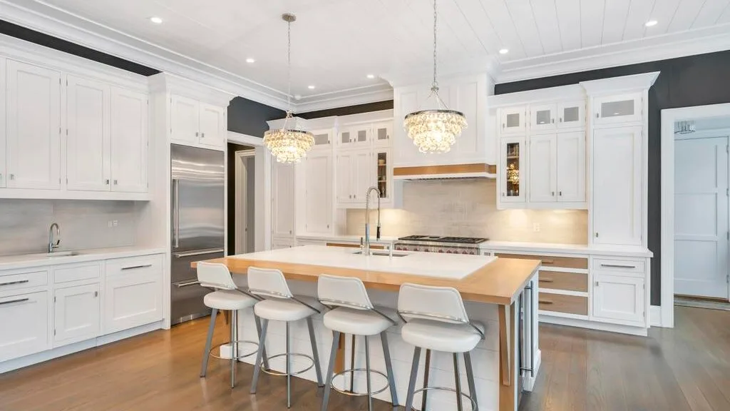 Una cocina luminosa con gabinetes blancos y una isla con asientos.