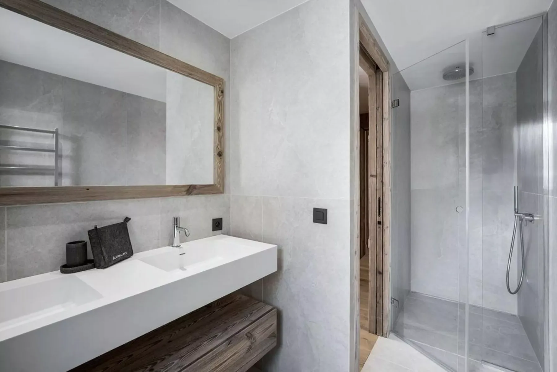 A modern bathroom with a long sink counter, mirror, and glass shower.