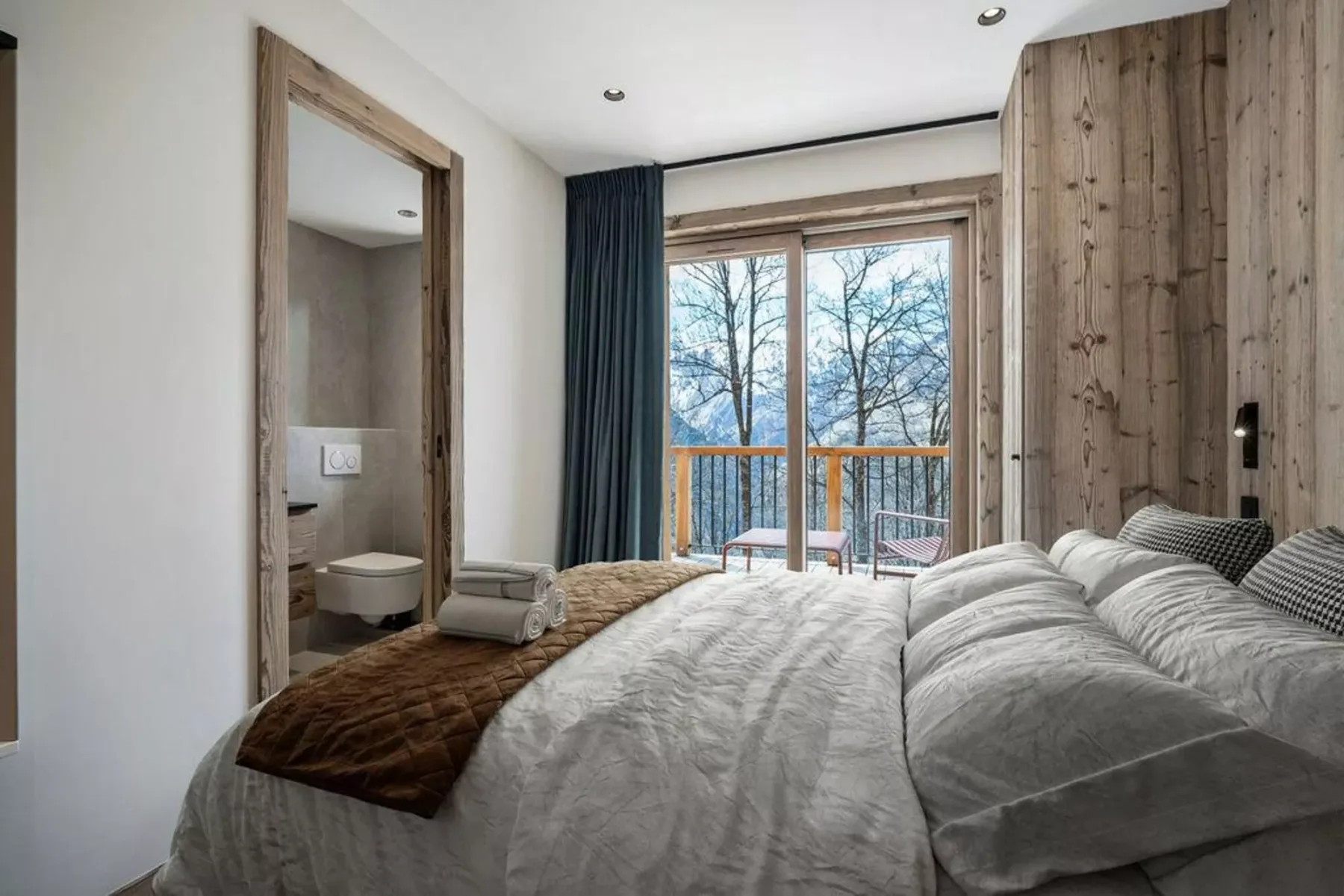 A bedroom with a bed facing glass doors and a balcony.