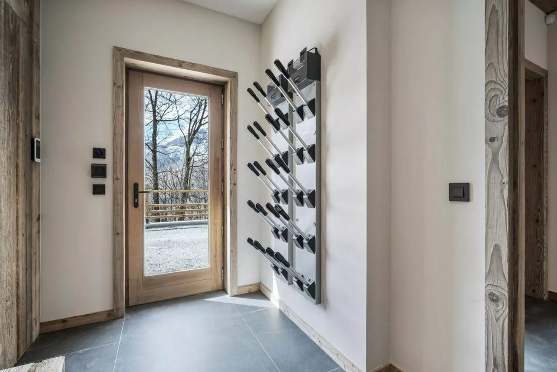 An entryway with a glass door and a wall-mounted ski rack.