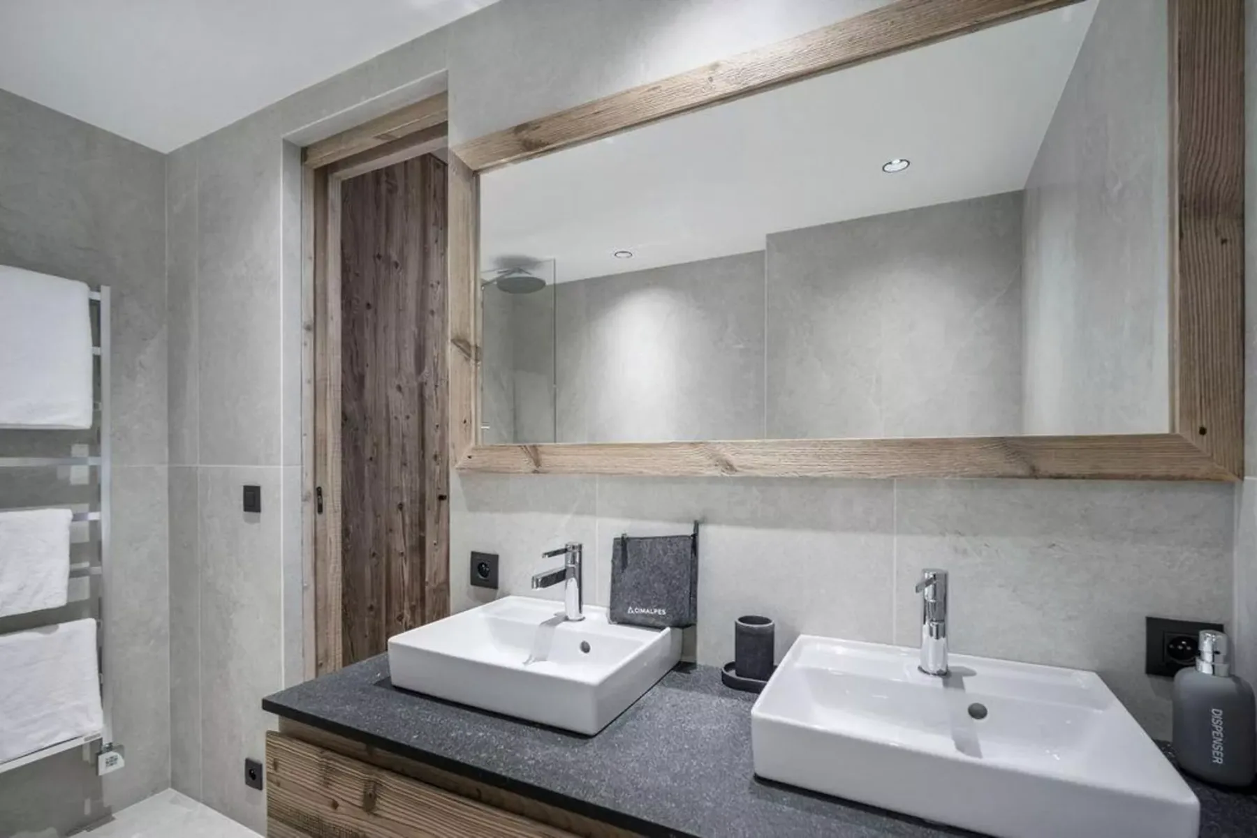 A bathroom with two sinks beneath a large mirror.