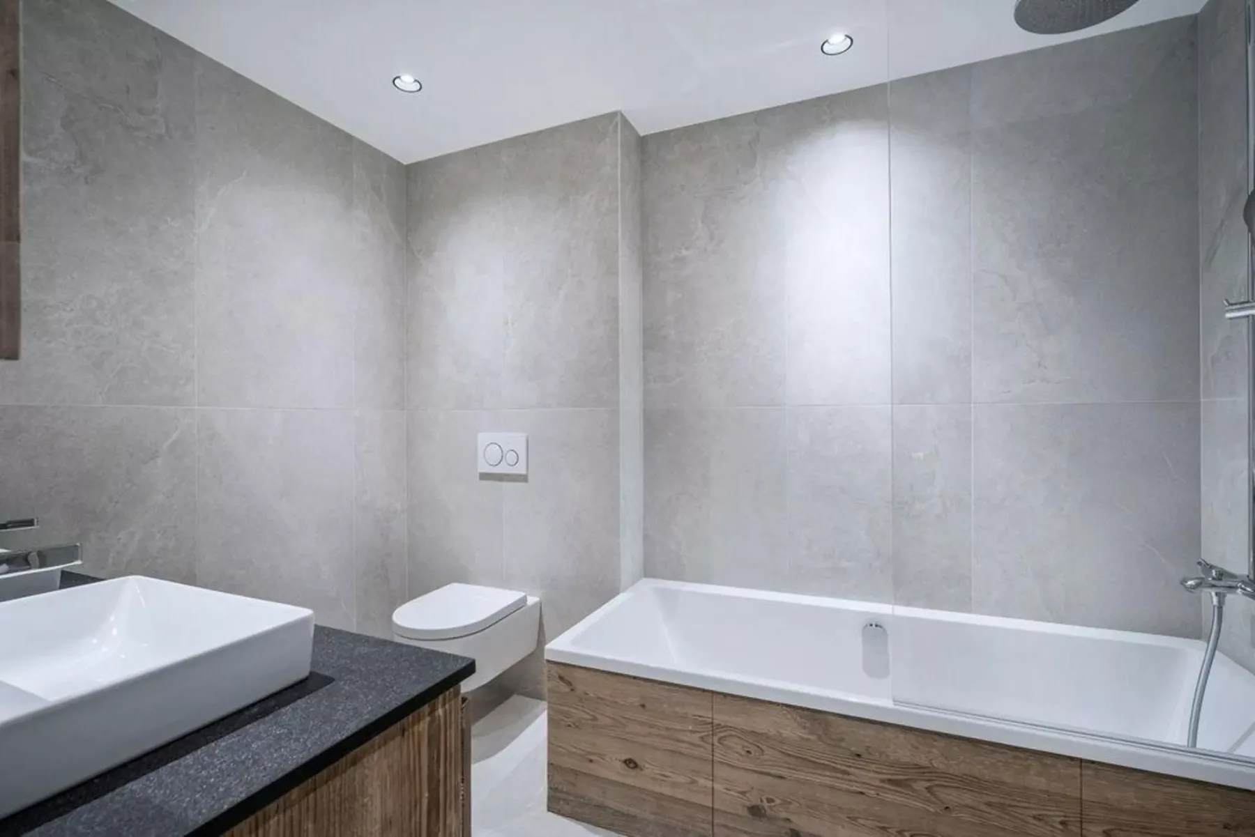 A modern bathroom with a bathtub, wall-mounted shower, and sink.