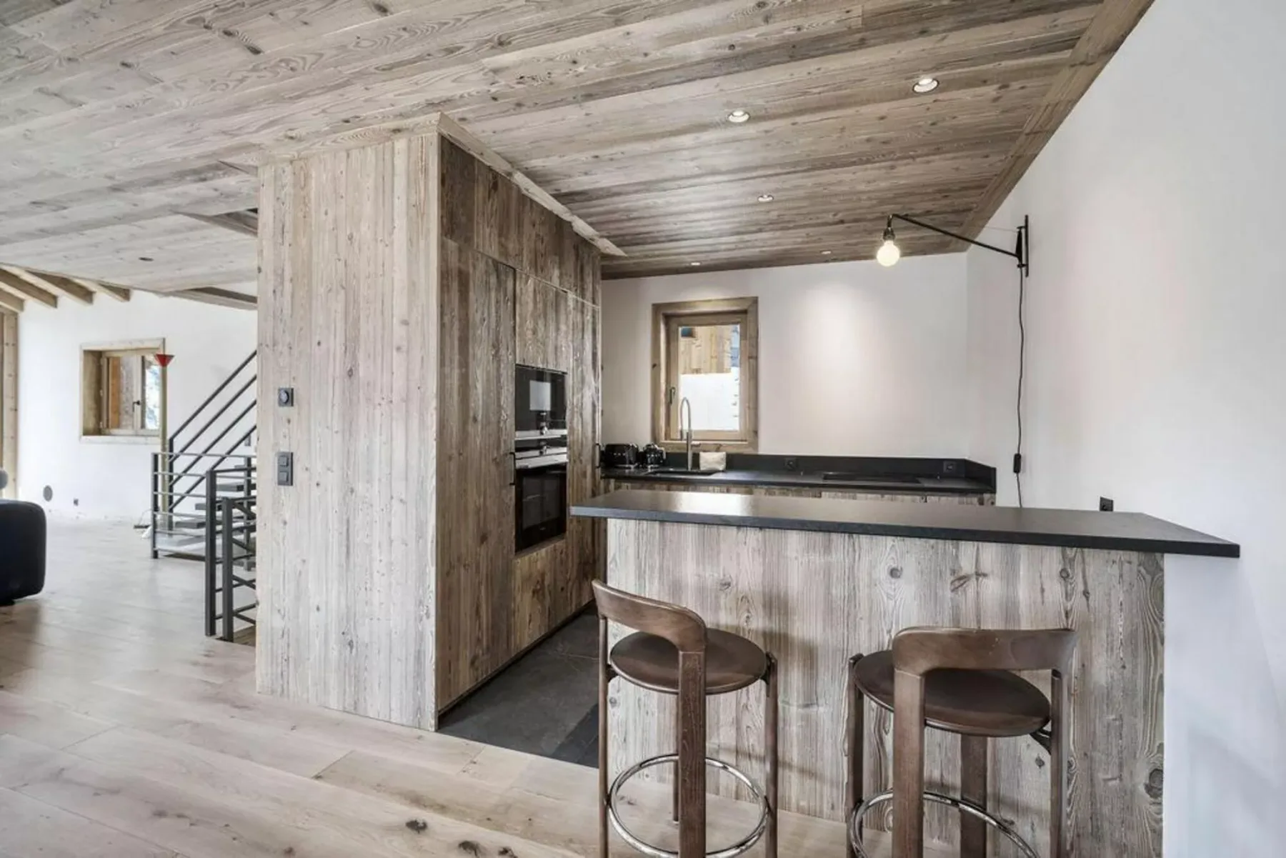 A modern kitchen with a dark countertop and two bar stools.