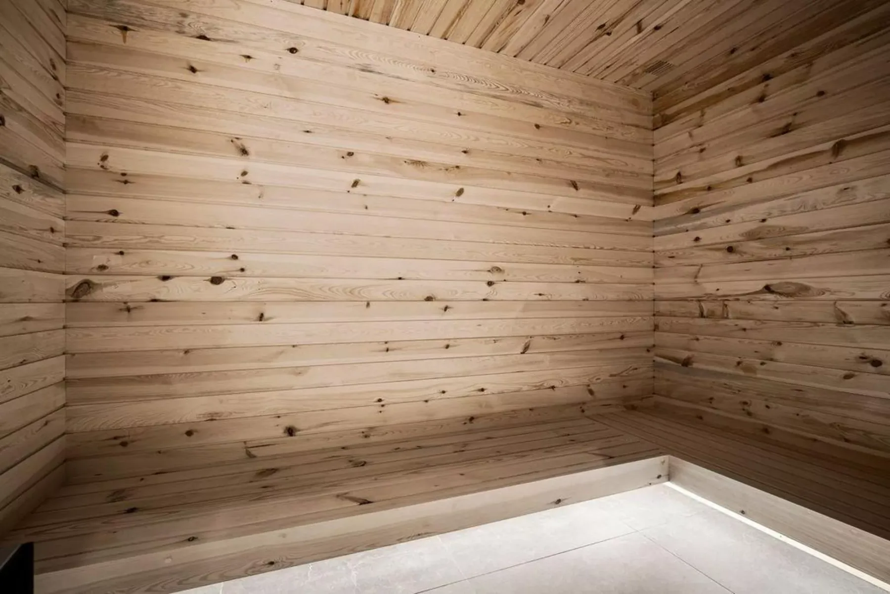 A wood-paneled sauna with a raised wooden bench.