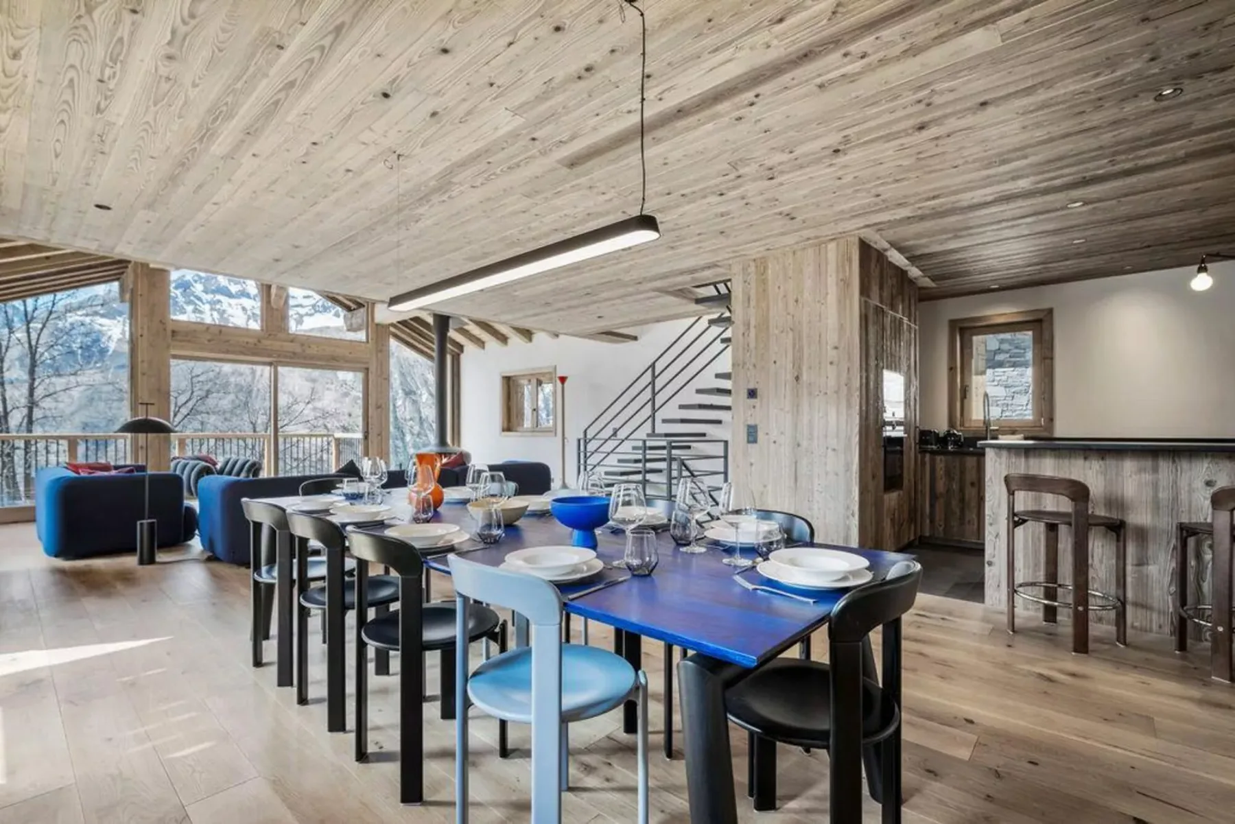 A dining area with tables and seating beside large windows.