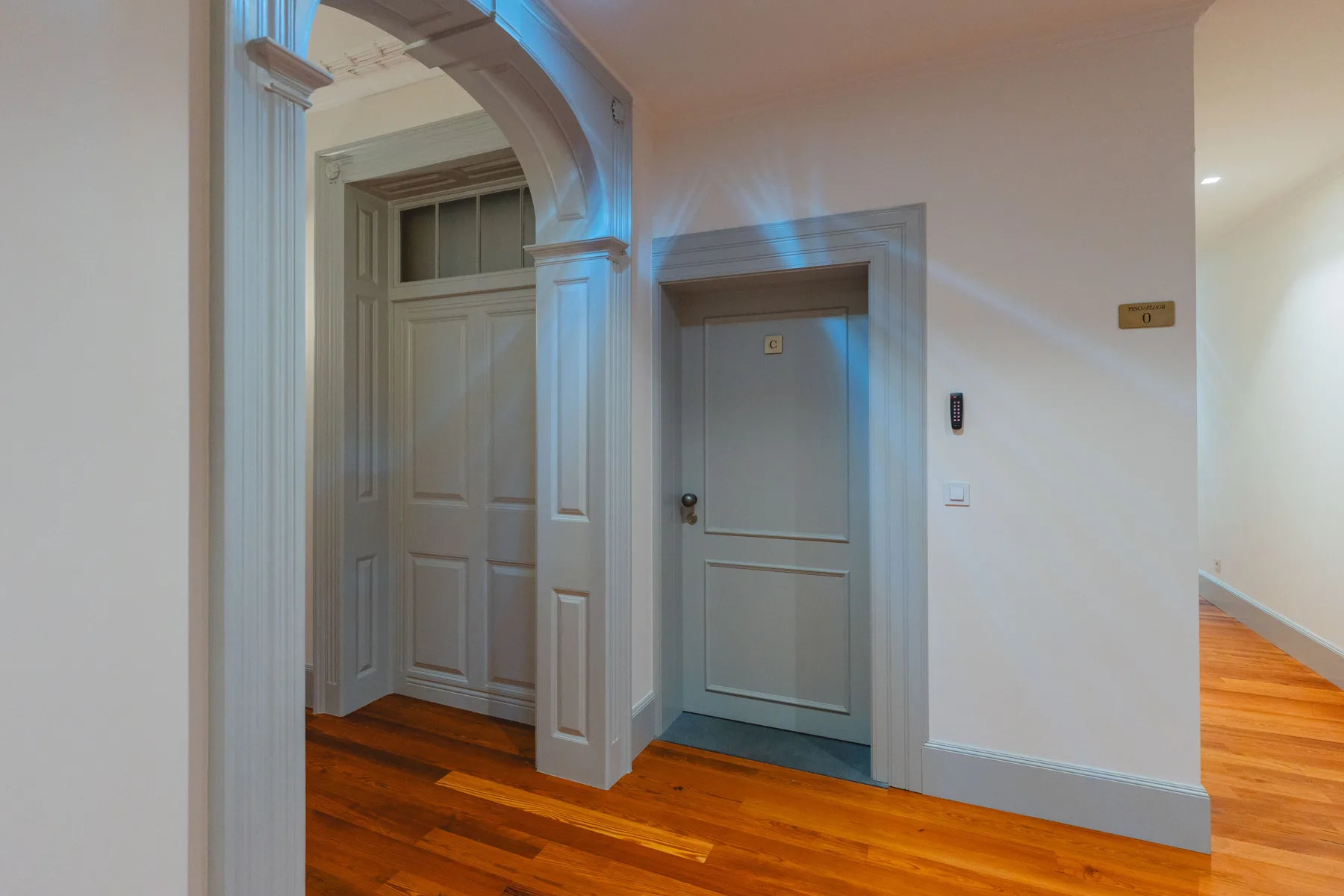 An interior hallway with wooden flooring and several doors.