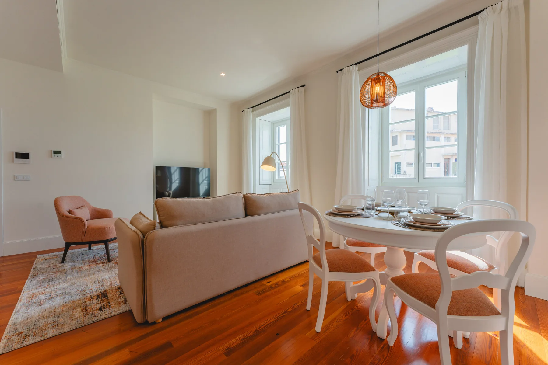 A bright living and dining area with seating, a television, and a set dining table.