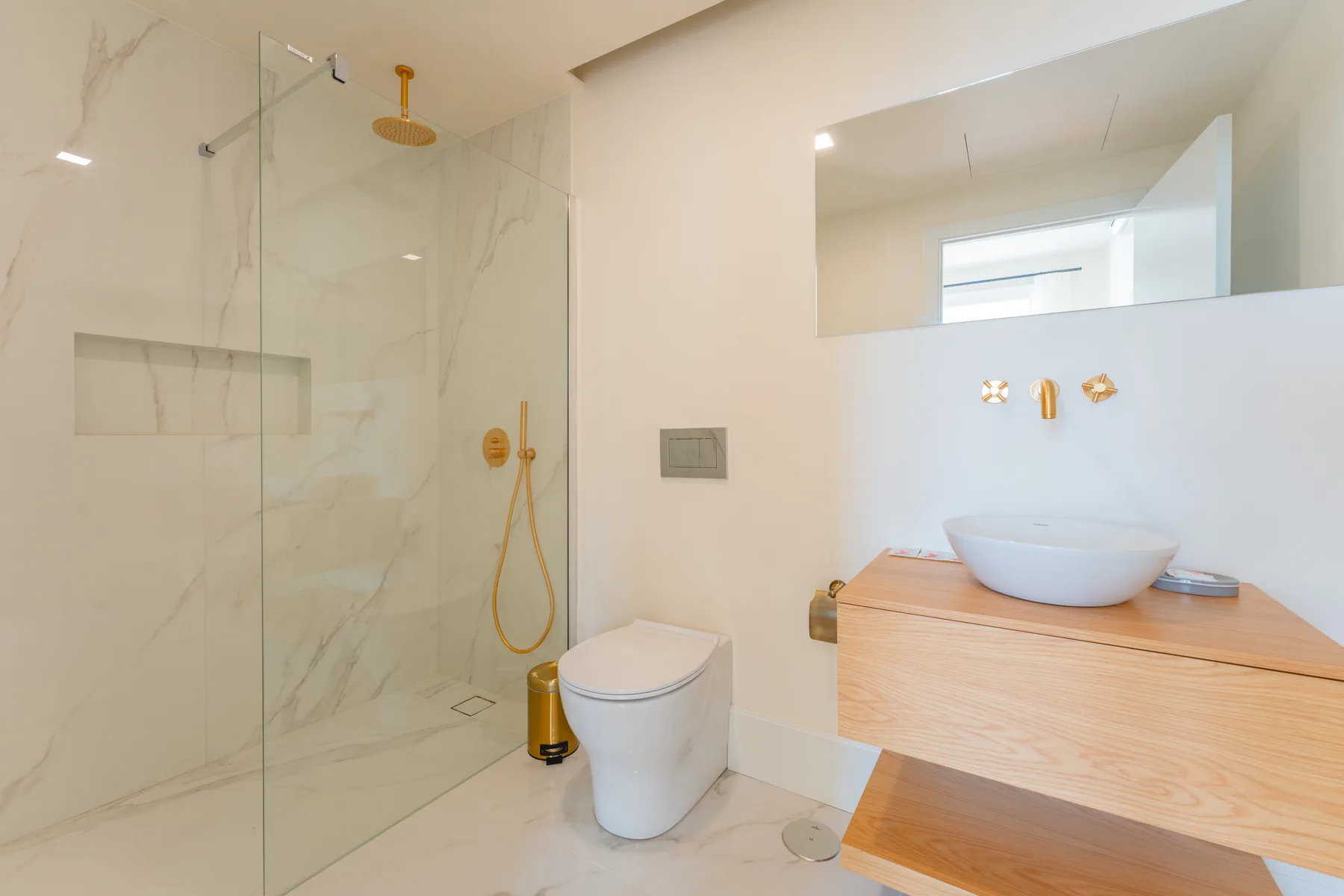A modern bathroom with a glass shower and a vessel sink on a wood vanity.