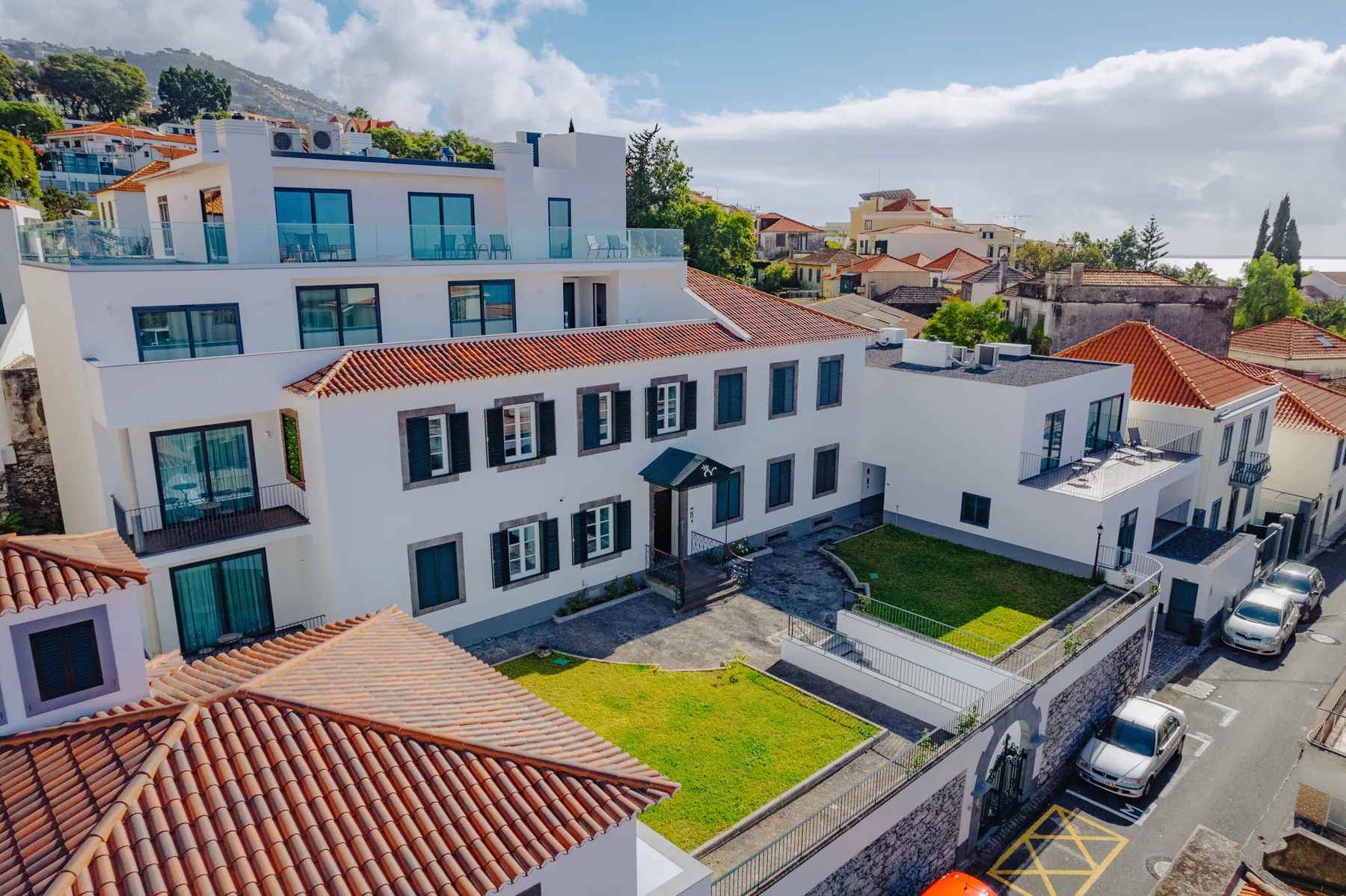 White residential buildings with red-tiled roofs overlook a small walled yard.