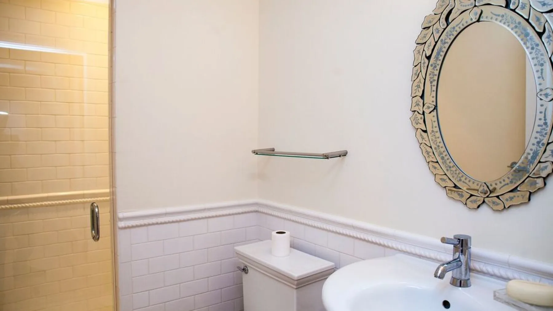 Un lavabo de baño con espejo y una pared de ducha revestida de azulejos.