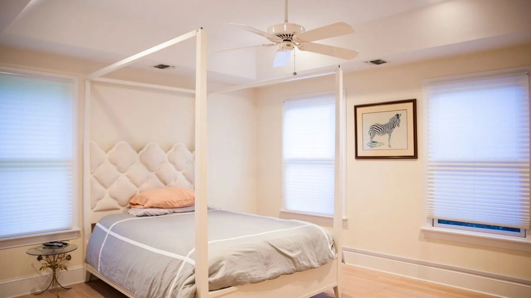 Dormitorio con una cama con dosel, ventanas y un cuadro en la pared.
