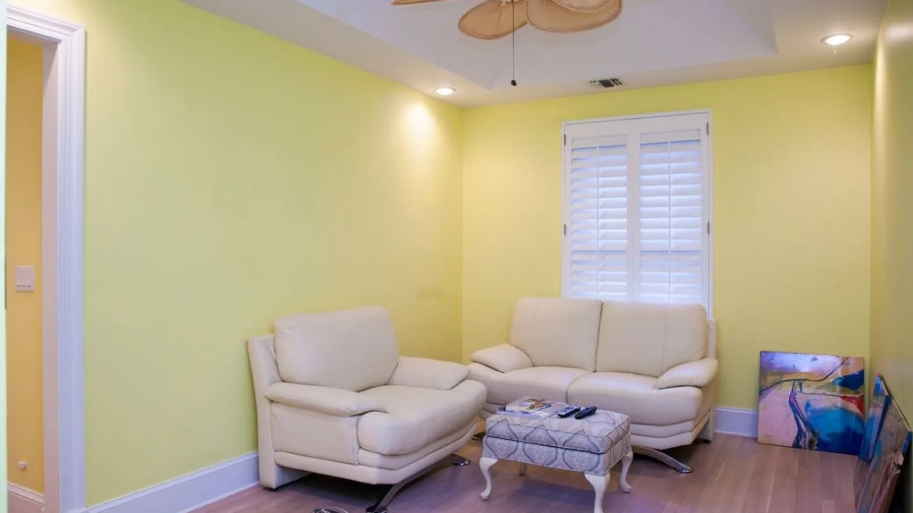 Una sala amarilla con asientos color crema y una pequeña mesa de centro.