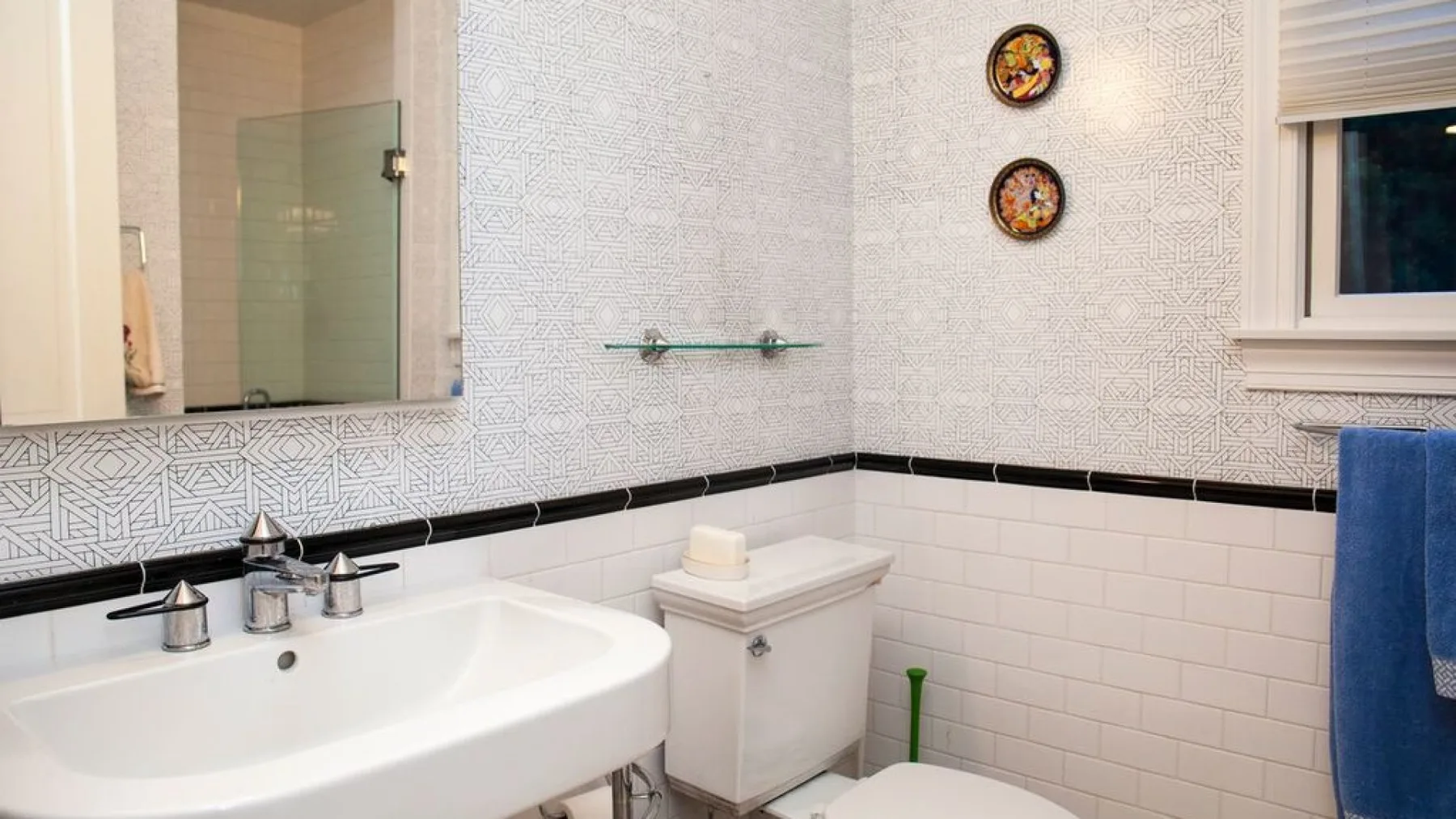 Un baño alicatado con lavabo, inodoro y espejo de pared.