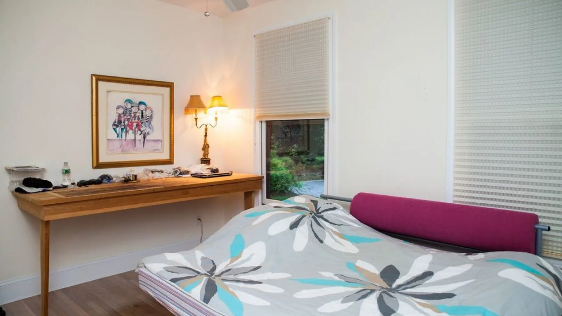 Un dormitorio con una cama cubierta con un edredón estampado de flores y un escritorio de madera.