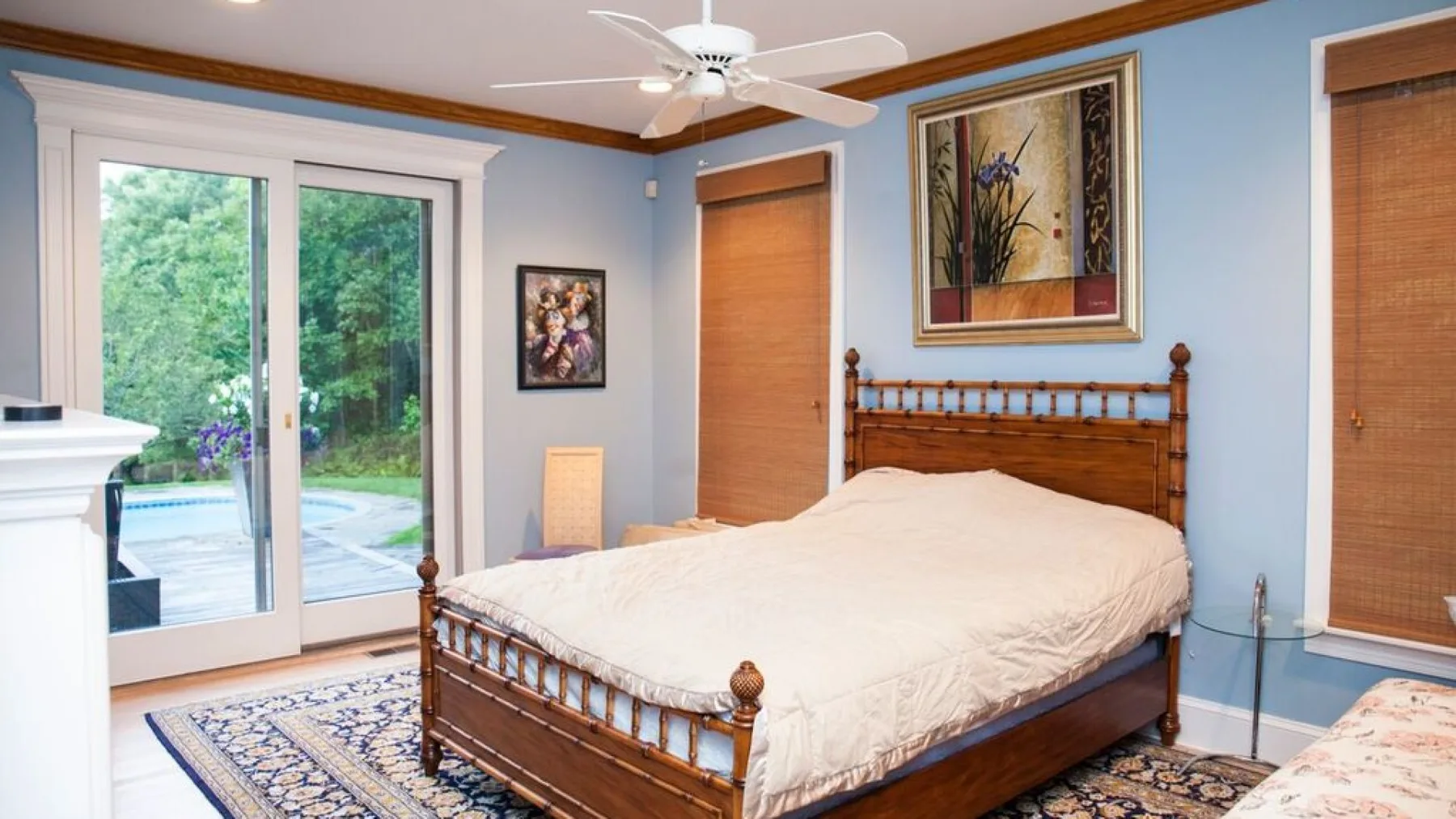 Un dormitorio con una cama de madera, ropa de cama clara y ventanas con vistas a la vegetación.