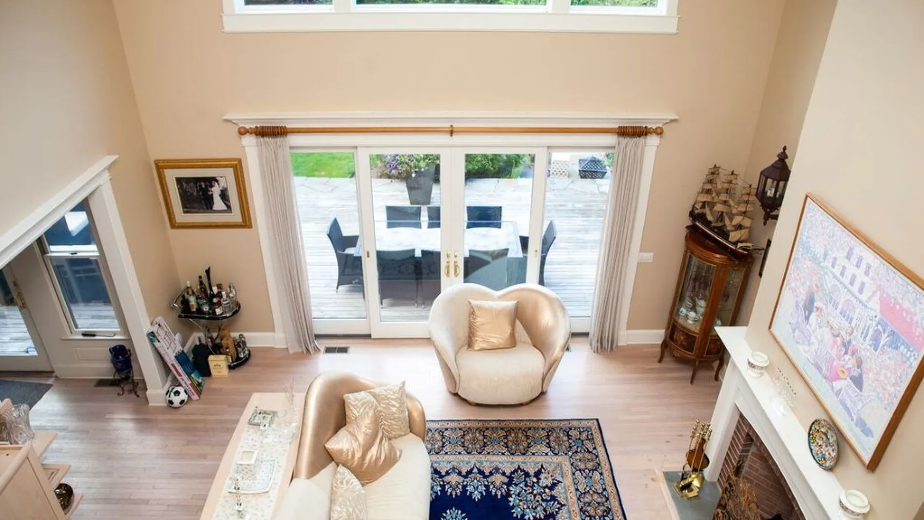 A bright living room with seating, a patterned rug, and glass doors opening to a deck.