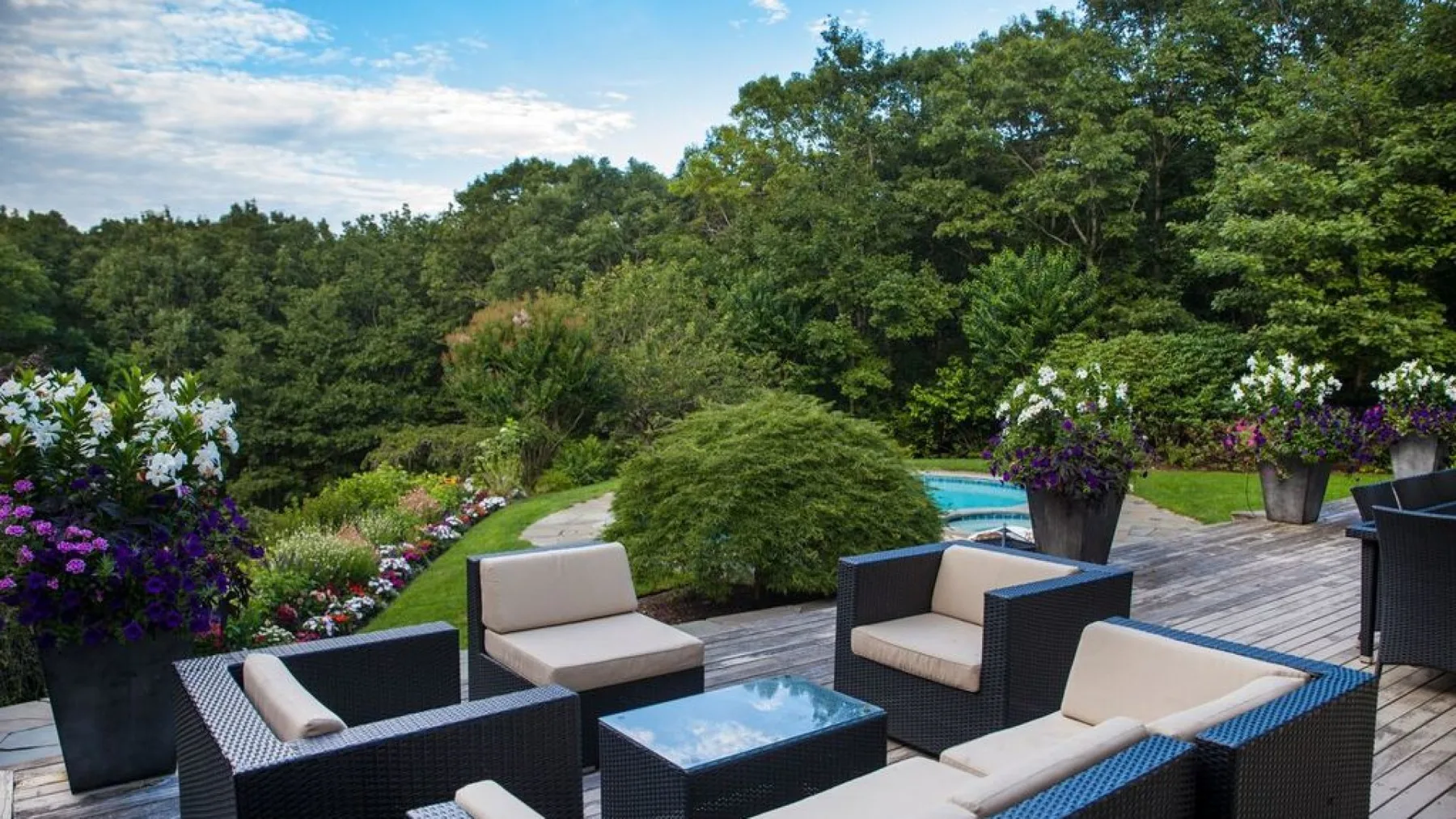 An outdoor seating area with cushioned furniture and a small pool amid greenery.