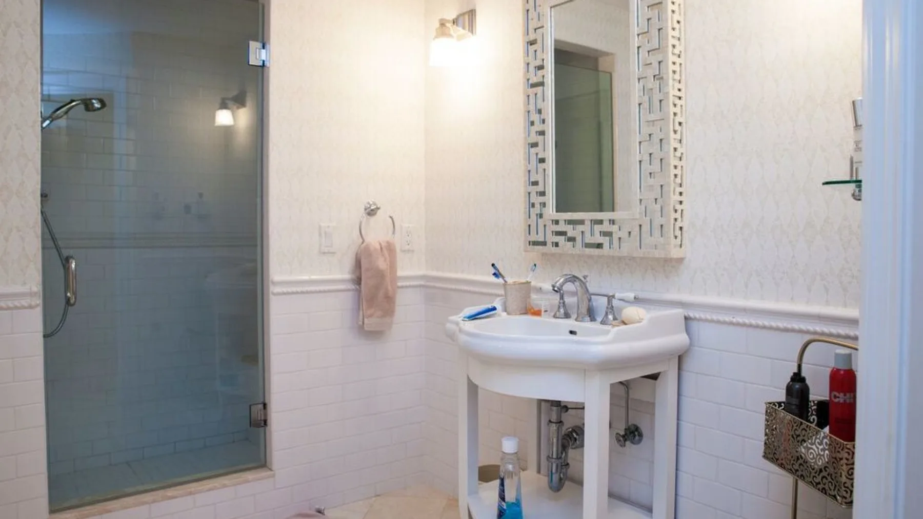 Un baño con lavabo de pedestal, espejo de pared y ducha de vidrio.