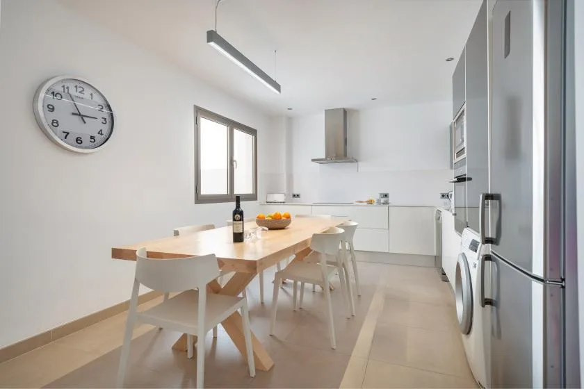 A bright kitchen and dining area with a wooden table and white cabinetry.