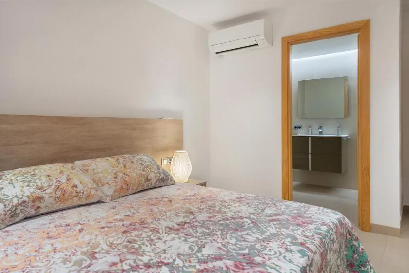 A bedroom with a floral-patterned bedspread and an open doorway to a bathroom.
