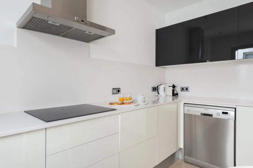 A modern kitchen with a cooktop, range hood, and stainless-steel dishwasher.